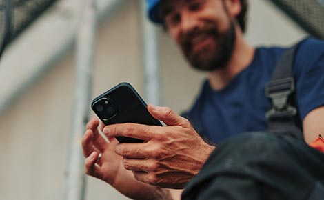 An electrical worker using a smartphone on a job site